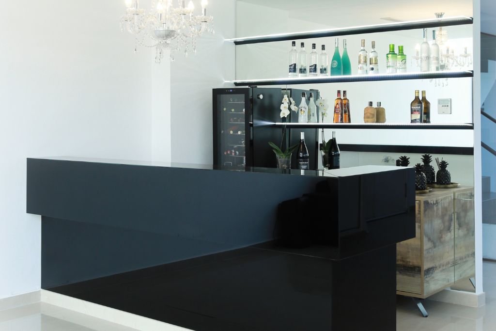 barra de bar hecha con vidrio ladado negro y una pared de espejos